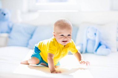Erkek yatakta güneşli kreş oynayan bebek