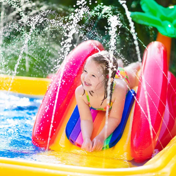 Menina que joga na piscina inflável do jardim — Fotografia de Stock