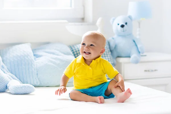 Baby pojke spelar på säng i soliga plantskola — Stockfoto