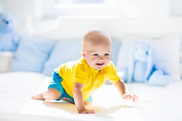 Baby boy playing on bed in sunny nursery — Stock Photo, Image