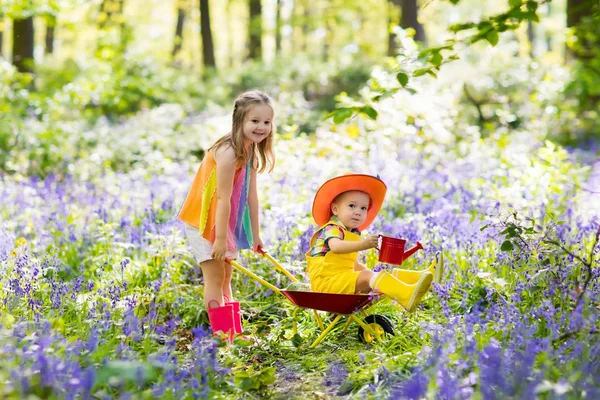 Kinder mit Blauglockenblumen, Gartengeräten — Stockfoto