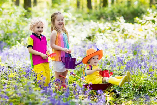 Dzieci z kwiatami bluebell, narzędzia ogrodnicze — Zdjęcie stockowe