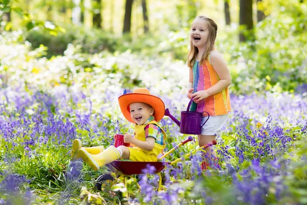 Τα παιδιά με bluebell λουλούδια, εργαλεία κήπου — Φωτογραφία Αρχείου