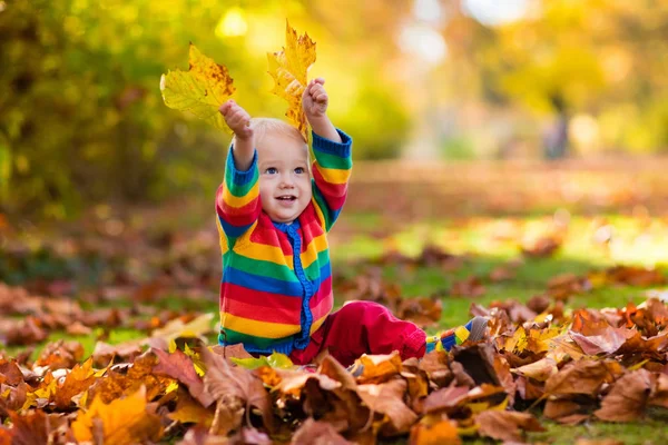 Barn i höst park. Kid med hösten lämnar. — Stockfoto