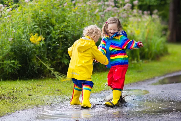 Los niños juegan bajo la lluvia y charco en otoño — Foto de Stock