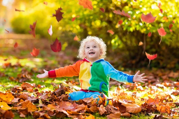 Dziecko w upadek park. Dziecko z jesieni pozostawia. — Zdjęcie stockowe