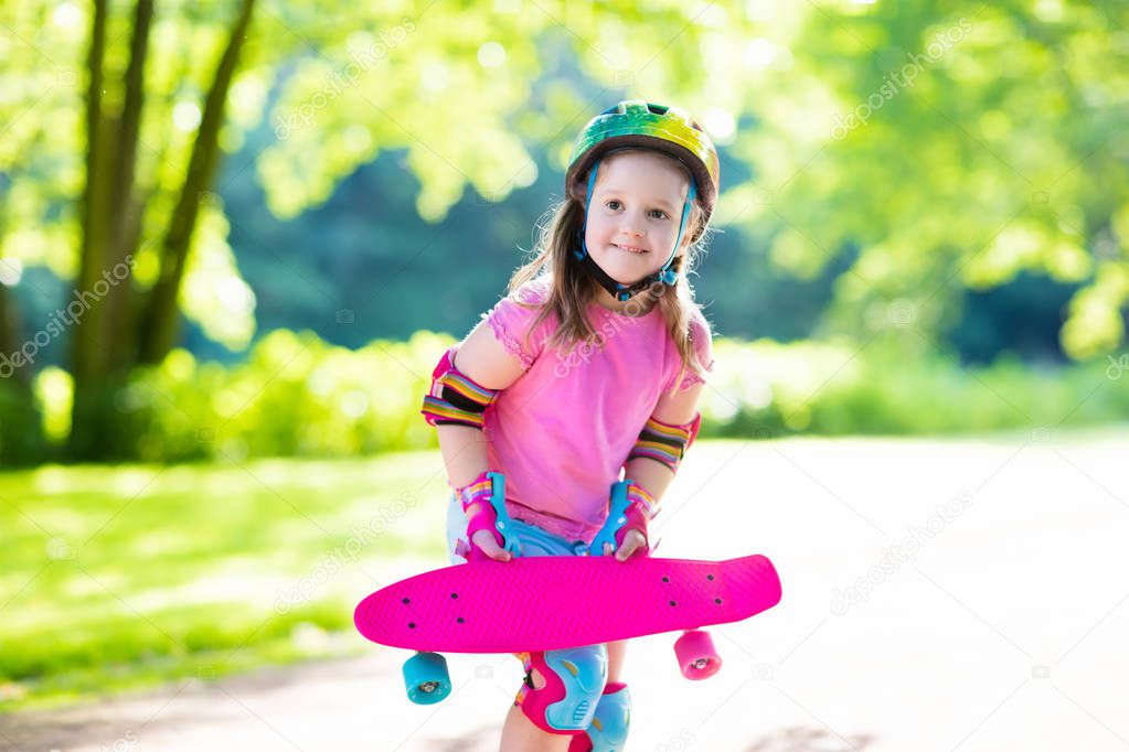 Child riding skateboard in summer park