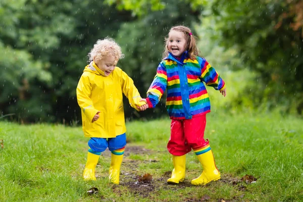 Los niños juegan bajo la lluvia y charco en otoño — Foto de Stock