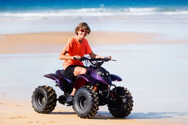 Teenager riding quad bike on beach — Stock Photo, Image