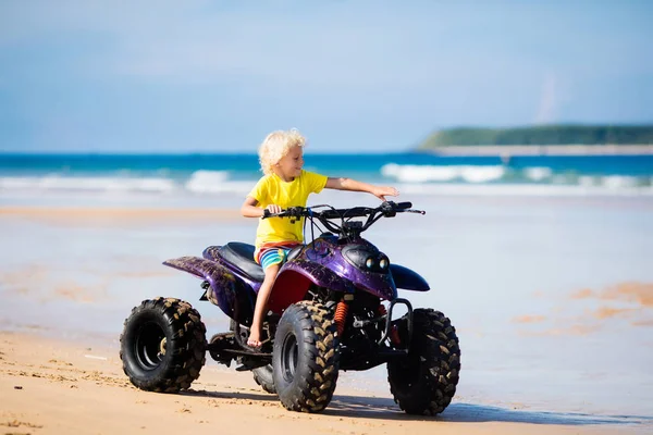 Barn på fyrhjuling på stranden. All - terrain fordon. — Stockfoto