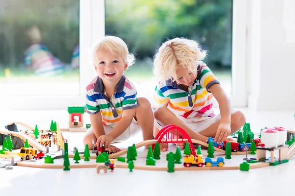 Children play wiht toy train. Kids wooden railway.