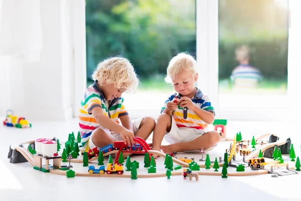 Los niños juegan con el tren de juguete. Ferrocarril de madera . —  Fotos de Stock