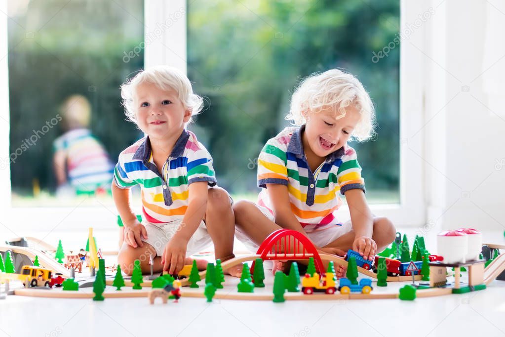 Children play wiht toy train. Kids wooden railway.