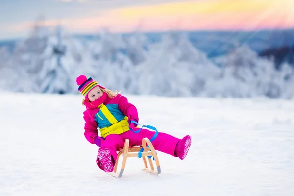 Dziecko grając w śniegu na sanie w winter park — Zdjęcie stockowe