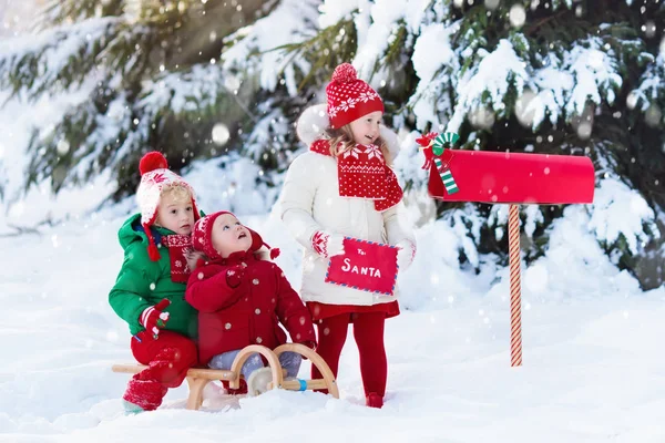 Crianças com carta ao Papai Noel na caixa de correio de Natal na neve — Fotografia de Stock