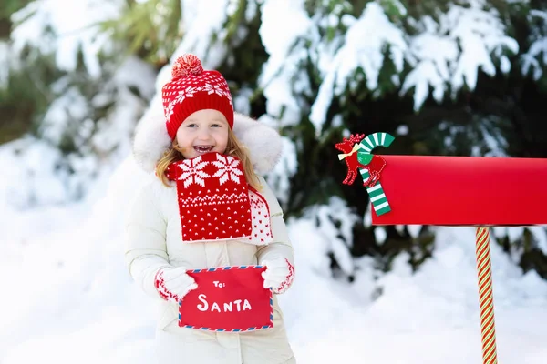 Ребенок с письмом к Санте на Рождество почтовый ящик в снегу — стоковое фото