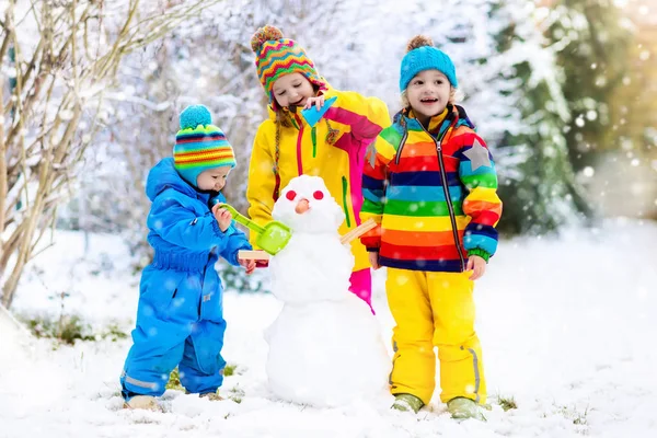 Barnen bygga snögubbe. Barn i snön. Vinternöje. — Stockfoto