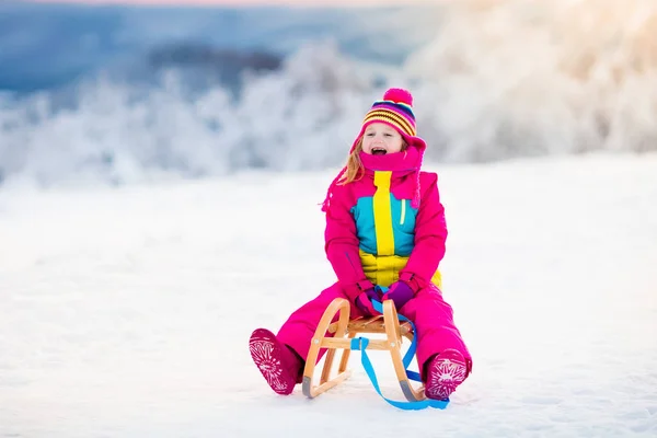 Niño jugando en la nieve en trineo en el parque de invierno —  Fotos de Stock