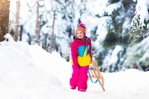 Kind spielt im Schnee auf Schlitten im Winterpark — Stockfoto