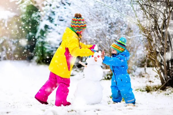 Barnen bygga snögubbe. Barn i snön. Vinternöje. — Stockfoto