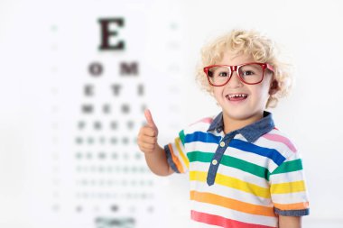 Child at eye sight test. Kid at optitian. Eyewear for kids. clipart