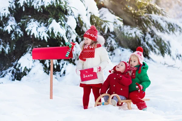 Děti s dopis do Santa na Vánoce mail box ve sněhu — Stock fotografie