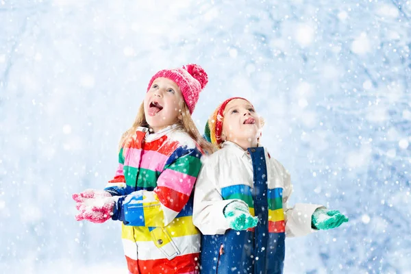 Kids playing in snow. Children play outdoors in winter snowfall.