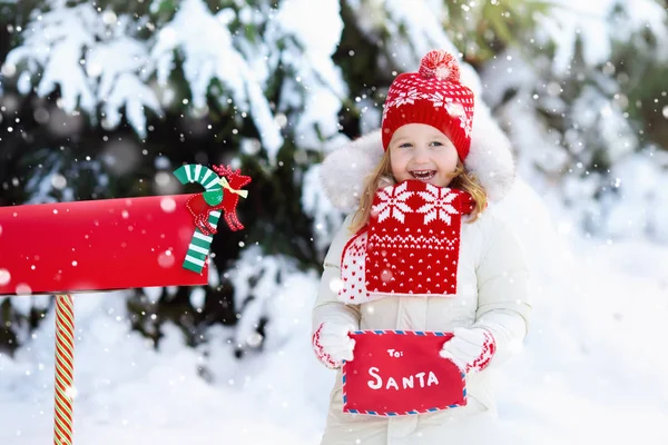 Enfant avec lettre au Père Noël à la boîte aux lettres dans la neige — Photo