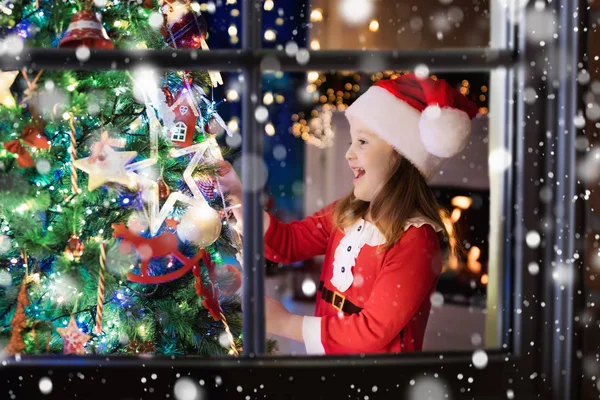 Child at Christmas tree and fireplace on Xmas eve — Stock Photo, Image