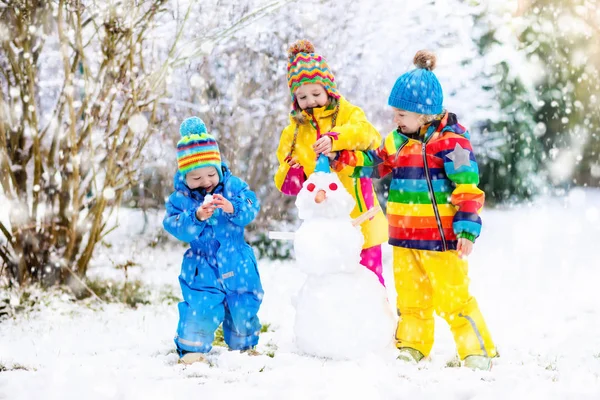 Kids building snowman. Children in snow. Winter fun.