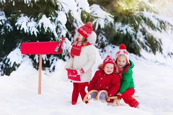 Děti s dopis do Santa na Vánoce mail box ve sněhu — Stock fotografie