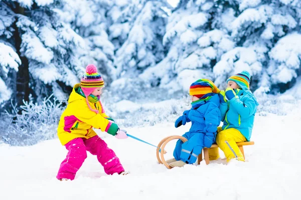 Miúdos em viagem de trenó. Crianças a patinar. Inverno neve diversão . — Fotografia de Stock