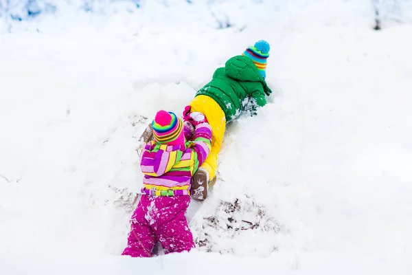 Kids playing in snow. Children play outdoors in winter snowfall. — Stock Photo, Image