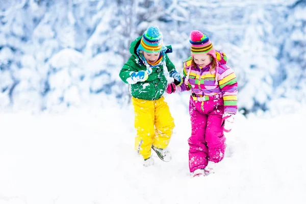 Crianças brincando na neve. Crianças brincam ao ar livre no inverno snowfall . — Fotografia de Stock