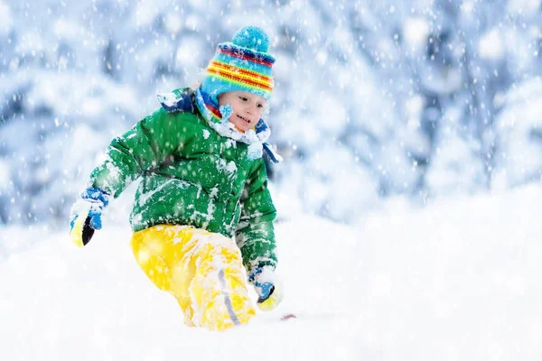 Child playing with snow in winter. Kids outdoors.