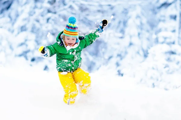 Child playing with snow in winter. Kids outdoors.