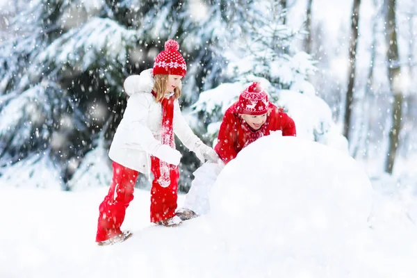 Des enfants construisant un bonhomme de neige. Des enfants dans la neige. Amusement d'hiver . — Photo