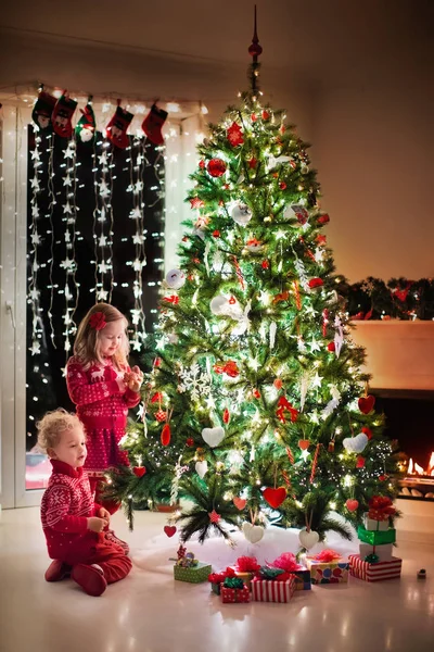 Kinderen bij de kerstboom en open haard op Xmas eve — Stockfoto