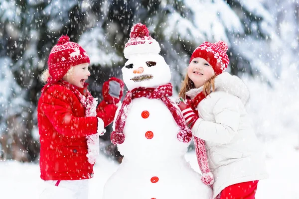 Bambini che costruiscono pupazzi di neve. Bambini nella neve. Divertimento invernale . — Foto Stock
