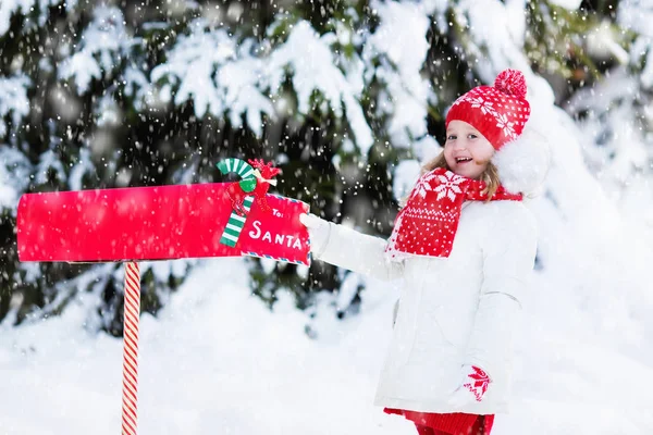 Dítě s dopis do Santa na Vánoce mail box ve sněhu — Stock fotografie