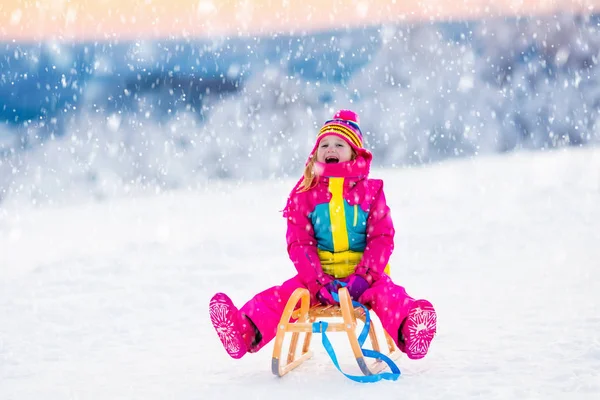 Kind spielt im Schnee auf Schlitten im Winterpark — Stockfoto
