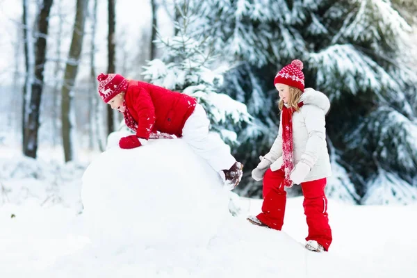 孩子们建设雪人。孩子们在雪地里。冬天的乐趣. — 图库照片