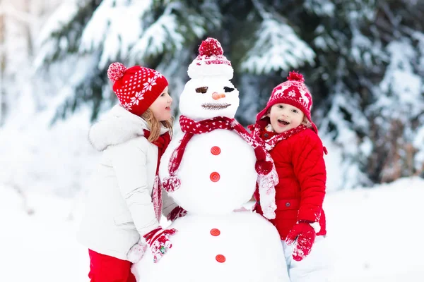 Bambini che costruiscono pupazzi di neve. Bambini nella neve. Divertimento invernale . — Foto Stock