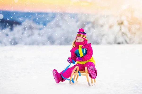 Criança brincando na neve no trenó no parque de inverno — Fotografia de Stock