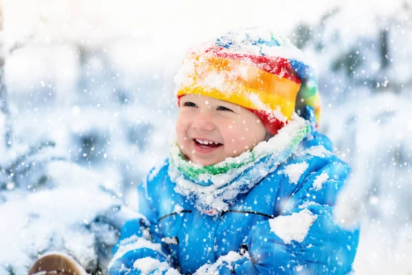 Baby playing with snow in winter. Child in snowy park. — Stock Photo, Image
