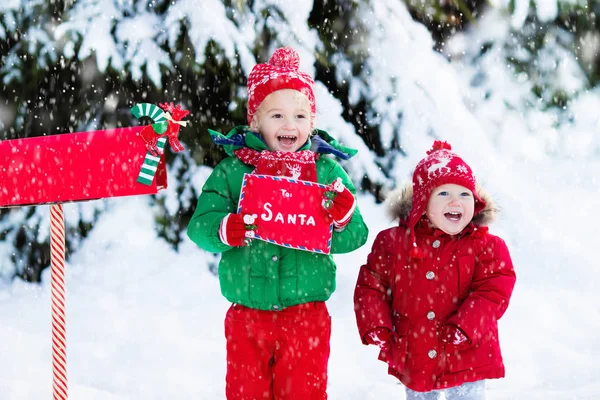 Dítě s dopis do Santa na Vánoce mail box ve sněhu — Stock fotografie