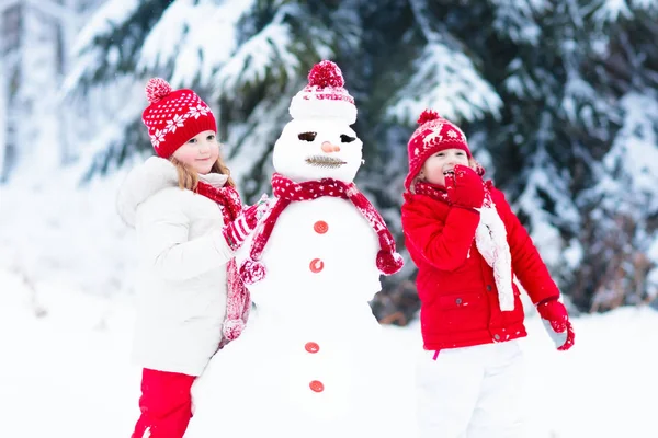 Bambini che costruiscono pupazzi di neve. Bambini nella neve. Divertimento invernale . — Foto Stock