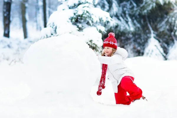 Des enfants construisant un bonhomme de neige. Des enfants dans la neige. Amusement d'hiver . — Photo