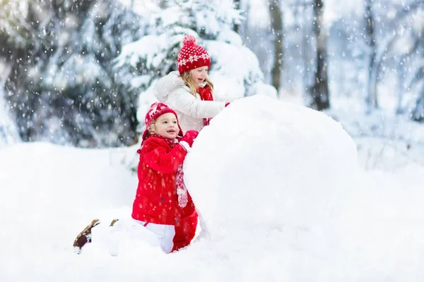 孩子们建设雪人。孩子们在雪地里。冬天的乐趣. — 图库照片