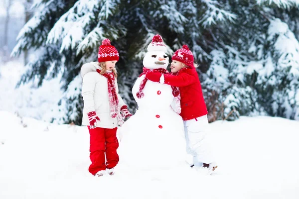 Crianças a construir boneco de neve. Crianças na neve. Diversão de inverno . — Fotografia de Stock